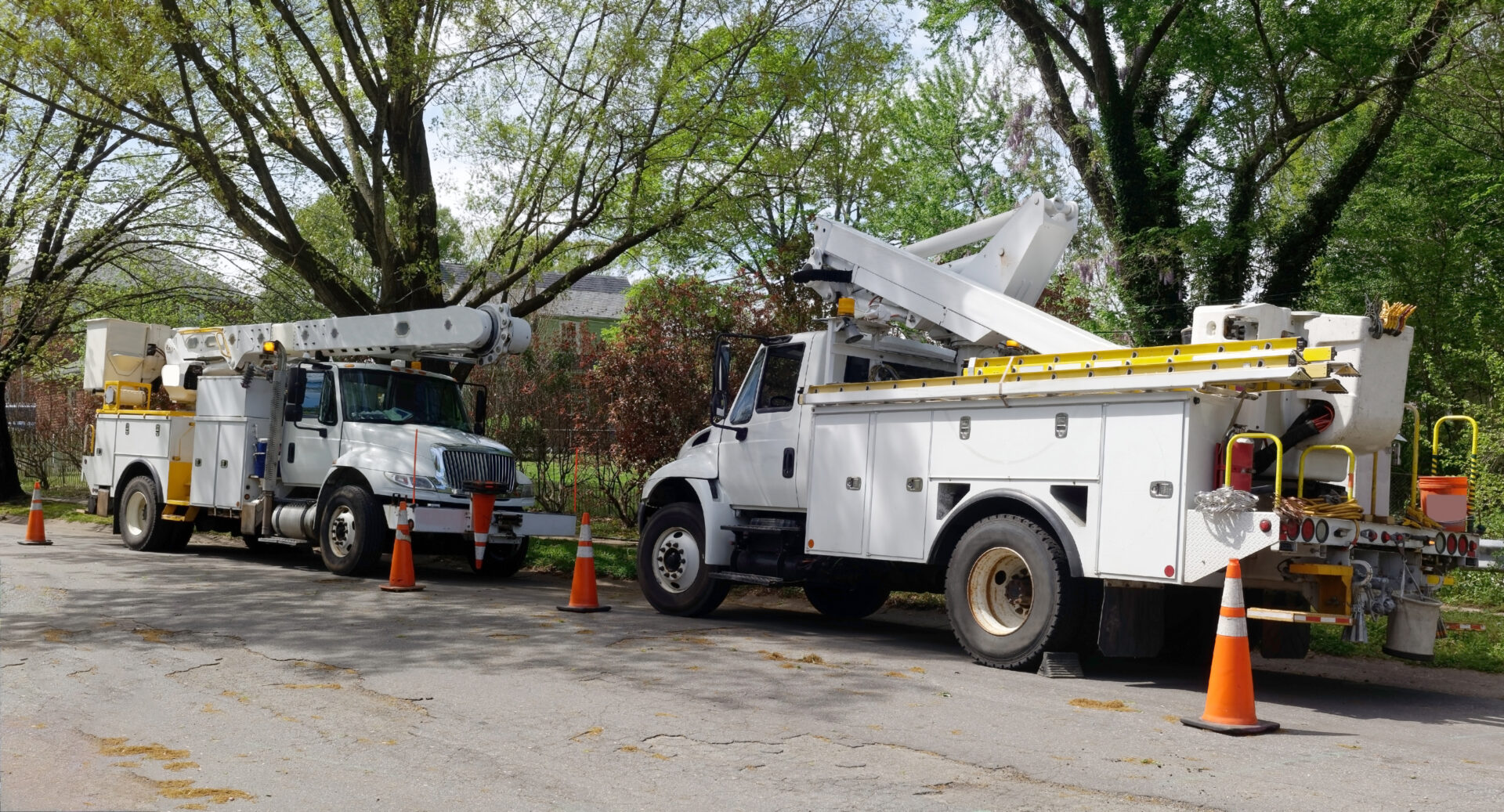 A white truck and a crane on the side of road.